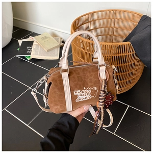 Detail der karamellbraunen Wildleder-Boston-Tasche mit Bärenstickerei und cremefarbenen Griffen