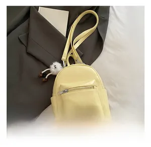 Detailed view of mini yellow PU leather backpack with a plush charm in a lifestyle setting