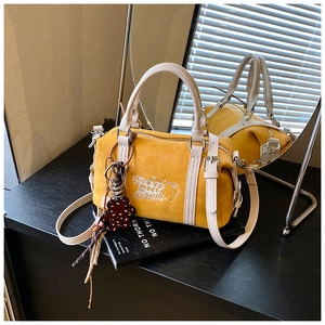 Detail der gelben Boston-Tasche mit 'Nice to meet you' Stickerei und Bären-Anhänger
