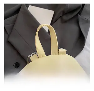 Close-up of a mini yellow PU leather backpack with a top handle and metal zipper details