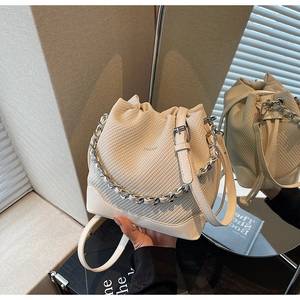 Detail of off-white drawstring bucket bag featuring twill fabric and silver chain handle