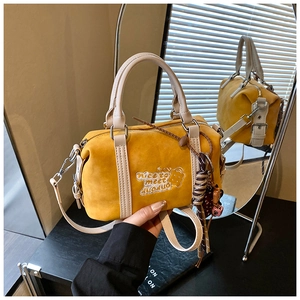 Detail der gelben Boston Bag mit weißer Stickerei und dekorativen Quasten an der Seite