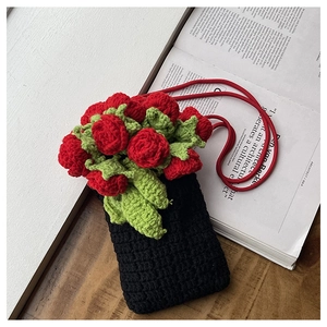Detailed macro view of handmade black knitted phone bag with red crochet roses