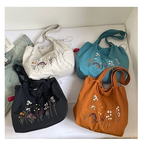 Detailed embroidery and drawstring closure on four colorful floral canvas tote bags