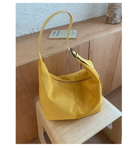 Macro view of yellow suede tote bag showing curved edge and matte texture