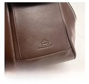 Macro shot of dark brown leather texture and neat stitching detail on a large handbag