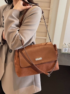 Brown vintage baguette bag with chain strap and leather texture mix worn by model