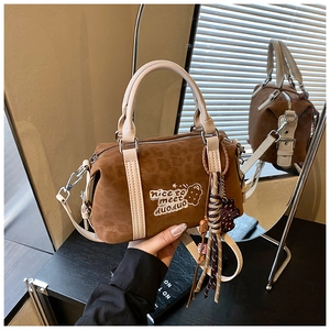 Detail der braunen Zylindertasche aus Wildleder mit Stickerei und buntem Quastenanhänger
