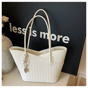 Detail of cream tote bag featuring V-shaped woven texture and smooth leather paneling