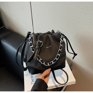 Detail of drawstring bucket bag featuring woven texture and silver chain strap
