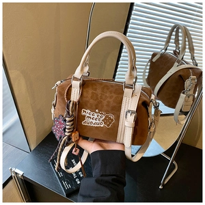 Detail einer braunen Wildleder-Bostontasche mit DUODUO-Stickerei und Spiegelreflexion