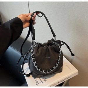 Detailed view of bucket bag with woven texture, silver chain strap, and ZHCNMA logo