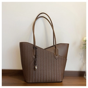 Detail of brown woven tote bag with herringbone pattern and leather trim and tassel