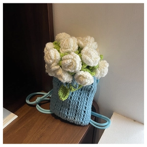 Detail of handcrafted crochet flower bag with white roses and soft blue knit texture