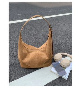 Close-up of brown suede hobo bag with adjustable strap on urban asphalt background