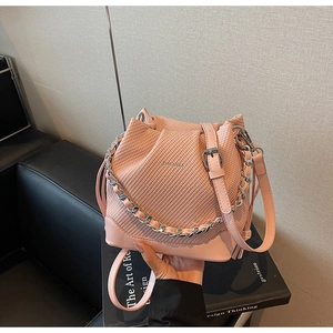 Detailed view of pink bucket bag with woven texture, metal chain, and leather strap