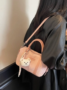 Chic pink pleated crossbody bag with plush bear charm and scarf on model