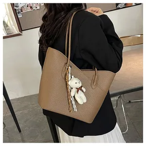 Braune Shopper-Tasche aus Leder mit Bären-Anhänger lässig über der Schulter getragen