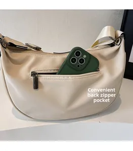 Detail view of the cream crescent bag with a functional back zipper pocket for storage