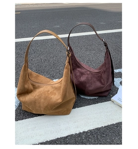 Detail of minimalist suede hobo bags in camel and dark coffee with wide straps