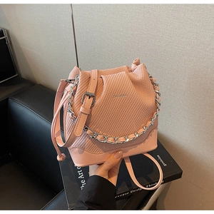 Detail view of pink woven texture bucket bag with silver chain and leather strap