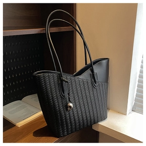 Detail of black woven texture shoulder bag with heart charm and slim double straps