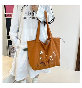 Detailed embroidery of colorful floral patterns on a caramel canvas tote bag surface