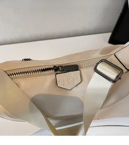 Close-up of black chrome zipper and beige fabric strap on stylish crossbody dumpling bag