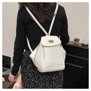 Creamy white leather backpack with silver buckle shown on a model in a modern office setting