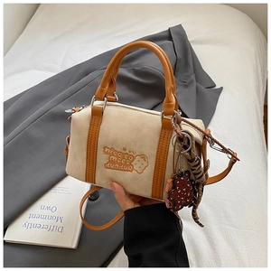 Detail einer beigen Boston Bag mit Bärenstickerei und Plüschanhänger im Lifestyle-Stil