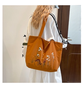 Detail of caramel tote bag with floral embroidery and textured fabric for daily use