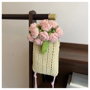 Detailed view of handmade crochet mini bag with pink flower knit decorations on a wooden hanger