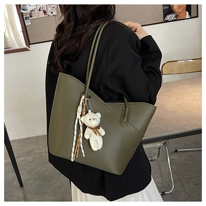 Nahaufnahme olivgrüne Shopper-Tasche mit Litschitextur und weißem Plüschbär-Anhänger