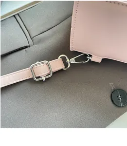 Detail of pink PU leather handbag showing adjustable shoulder strap and silver metal hooks