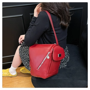 Detail of a dark red glossy leather shoulder bag featuring unique silver zipper styling