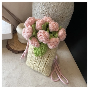 Macro view of hand-knitted beige bag featuring 3D pink rose and green leaf details