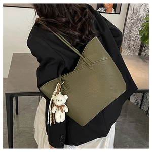 Detail der olivgrünen Tote-Bag aus genarbtem Leder mit Bärenanhänger an einer Frau