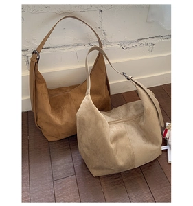 Detail of coffee brown and cream beige suede hobo bags with adjustable silver buckles