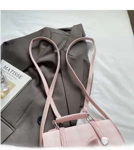 Detail of light pink plaid handbag with adjustable strap on gray blazer outfit