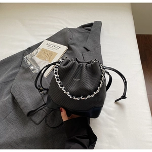 Detail of black woven bucket bag with silver chain and ZHCNMA logo on white fabric