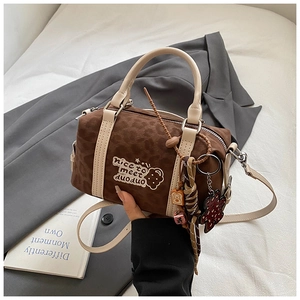 Detail einer braunen Boston-Tasche mit Leopardenmuster, Bärenanhänger und Webknoten