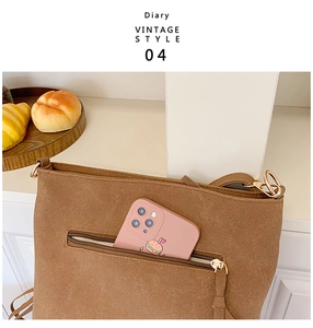 Close-up of vintage brown suede crossbody bag with golden metal zipper and phone pocket