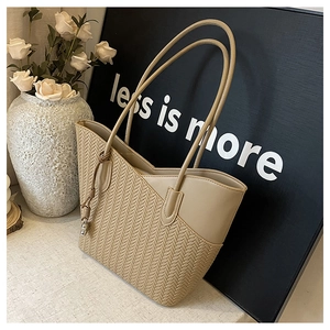 Detail of beige tote bag with herringbone weave texture and smooth leather finish