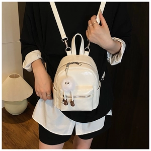 Close-up of white glossy mini backpack featuring a plush charm and silver hardware