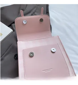 Detail of light pink plaid handbag featuring dual magnetic metal buckles and interior lining