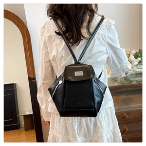 Detailed back view of a black leather backpack with metal plaque and side zipper accents