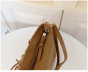 Gros plan du sac bandoulière en daim marron avec détails de franges et zip doré