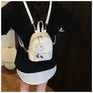 Mini white faux leather backpack for women with a playful plush eye charm accessory
