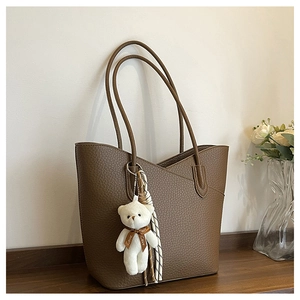 Nahaufnahme braune Tote Bag aus Leder mit Plüschbär-Anhänger und dekorativem Halstuch
