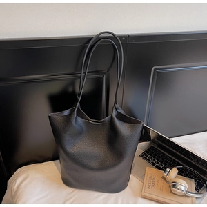 Close-up of a large black leather tote bag featuring a textured lychee grain finish